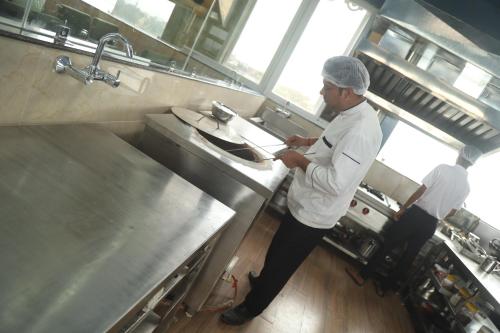 a man standing in a kitchen preparing food at Geetanjali International Annex a unit of Geetanjali International in Deoghar