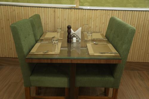 a table with two green chairs at a restaurant at Geetanjali International Annex a unit of Geetanjali International in Deoghar