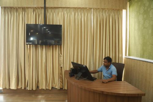 a man sitting at a desk with a laptop at Geetanjali International Annex a unit of Geetanjali International in Deoghar