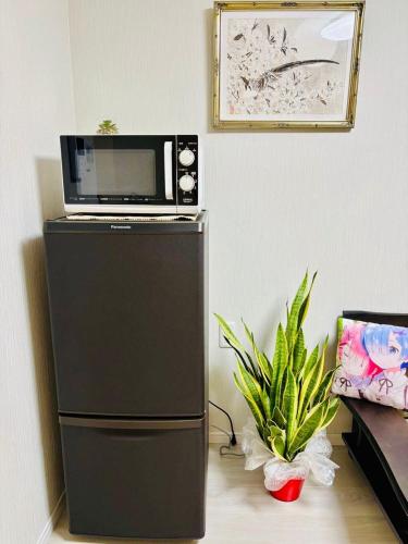 a microwave sitting on top of a refrigerator at Sakura桜ノ宮ヴィラ in Osaka
