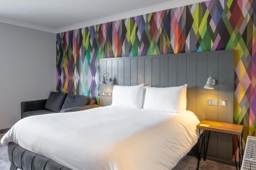 a bedroom with a large bed and a colorful wall at Village Hotel Cardiff in Cardiff