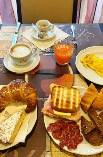 a table with plates of breakfast foods and cups of coffee at Hotel Cavour in Rieti