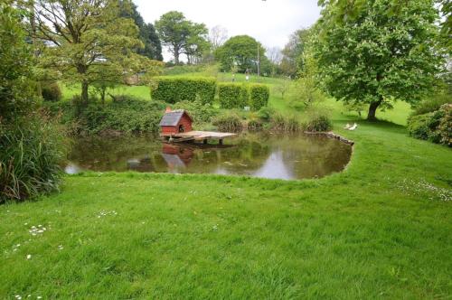 a house in the middle of a pond in a park at Finest Retreats - Cherry at Buckland Court in Slapton