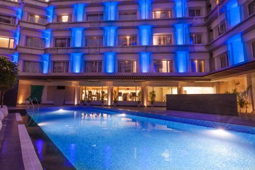 a swimming pool in front of a building with blue lights at Pharos Hotels in Chennai