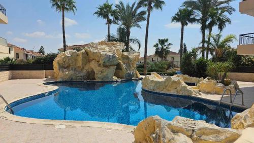 a swimming pool with rocks in a resort at Mediterranean Sunrise Apartments A2 in Voroklini