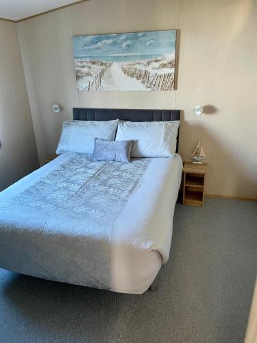 a bedroom with a large bed with blue sheets and pillows at Summer Breeze-Hoburne Cotswolds in South Cerney