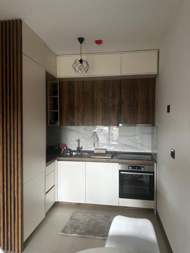 een keuken met witte kasten en een zwart apparaat bij Hill Apartment in Podgorica
