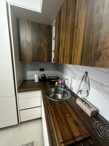 una piccola cucina con lavello e mobili in legno di Hill Apartment a Podgorica