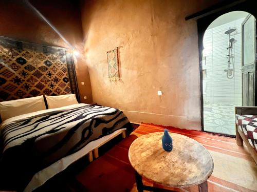 a bedroom with a bed and a table and a window at Riad La Perle Tamnougalte in Agdz