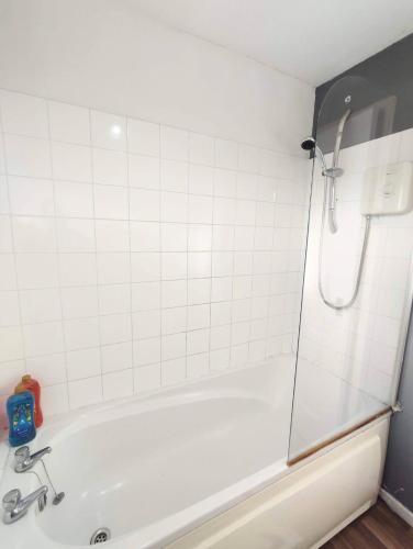 a white bath tub with a shower in a bathroom at Comfort Palace in Newcastle upon Tyne