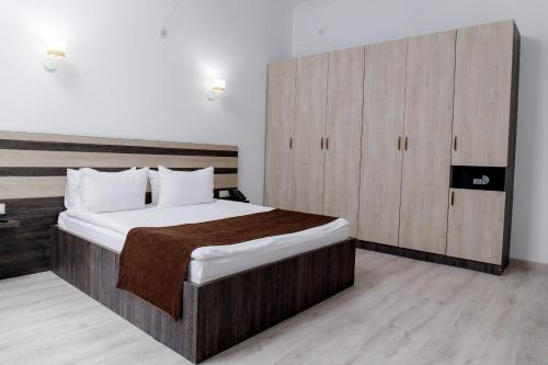 a bedroom with a large bed and a wooden cabinet at Infinity Plaza Hotel in Atyraū