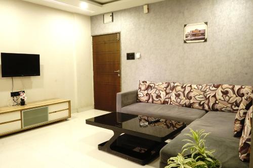 a living room with a couch and a tv at STAY10 Apartment Hotel in Indore