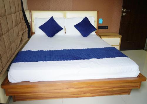 a bed with blue pillows on it in a room at STAY10 Apartment Hotel in Indore