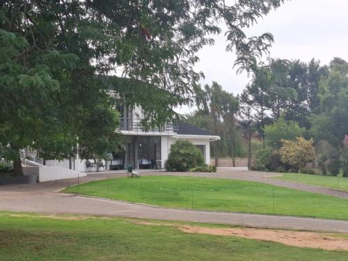 a large white house with a grassy yard at Skylight Guest House in Harrismith