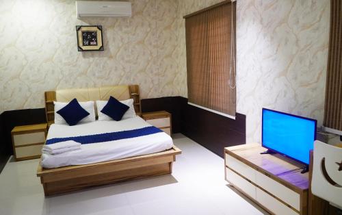 a bedroom with a bed and a laptop on a table at STAY10 Apartment Hotel in Indore