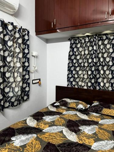 a bedroom with a bed with a comforter and curtains at Madura Homestay - Gorgeous Home with 2BHK 5 minutes from NH44 in Madurai
