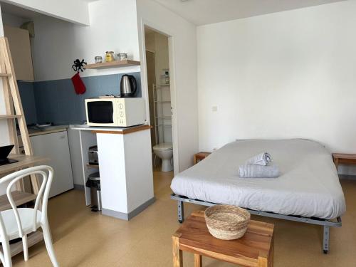 Cette petite chambre comprend un lit et un four micro-ondes. dans l'établissement ღ Le Funny - Studio Proche Plage & Parking gratuit, à La Rochelle