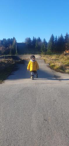 a child in a yellow raincoat walking down a road at Oddych v Rajeckých Tepliciach v samostatnom rodinnom dome in Rajecké Teplice