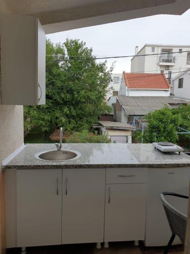 un bancone da cucina con un lavandino e una finestra di Dzenan apartmani a Dobra Voda