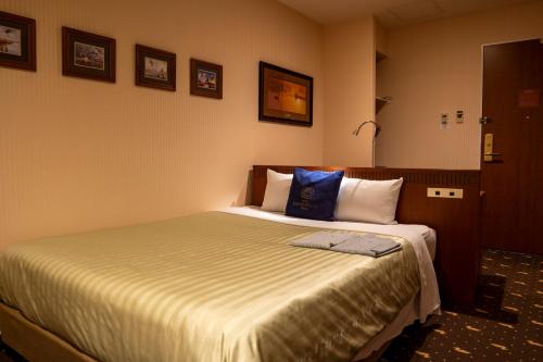 a bedroom with a bed with a blue pillow on it at Hotel Boston Plaza Kusatsu in Kusatsu
