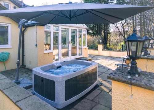 a hot tub with an umbrella on a patio at Acorns with own hot tub, romantic escape, close to Lyme Regis in Uplyme