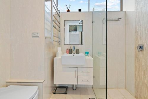 a white bathroom with a sink and a shower at Sparkling Bondi Views in Sydney