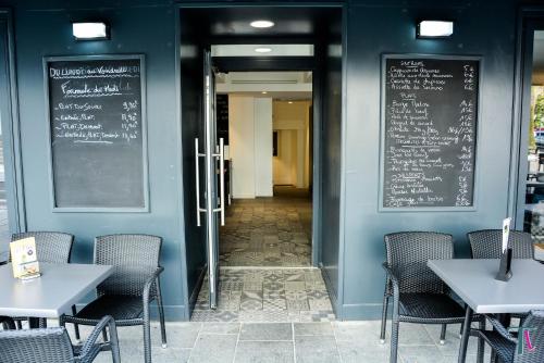 a dining room with tables and chairs and a chalkboard at Le Matisse Pau Centre in Pau