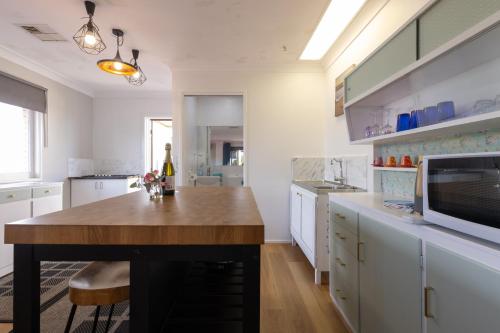 a kitchen with white cabinets and a wooden table at Zen Escape Guest House " Location 1" - Three listings - Romantic Escape, Cozy Delight, Oasis Suite in Brisbane