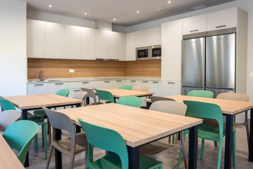 a classroom with wooden tables and green chairs at Albergue Sancho El Fuerte in Tudela