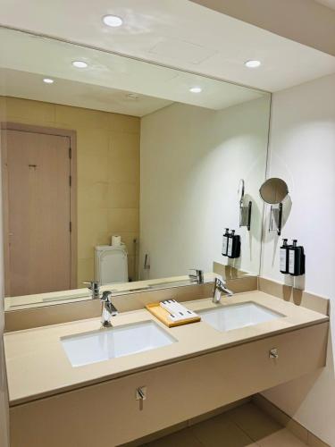 a bathroom with two sinks and a large mirror at The Hive Retreats in Yas Island in Abu Dhabi