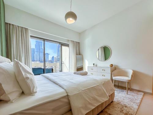 a white bedroom with a large bed and a window at Spectacular Burj Khalifa View, 2BR Luxury Apartment by SBH in Dubai