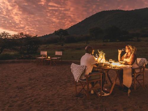 a group of people sitting at a table in the sand at Thaba eNtle Private Boutique Game Farm in Thabazimbi