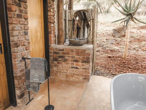 a bathroom with a brick wall and a bath tub at Thaba eNtle Private Boutique Game Farm in Thabazimbi