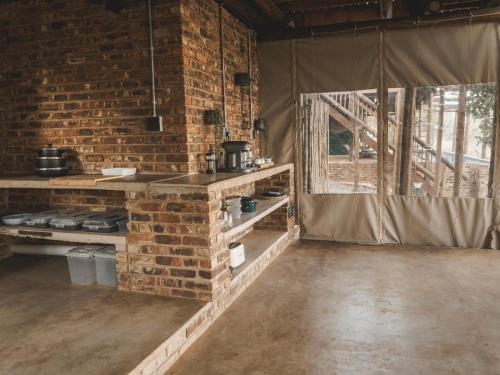 an empty room with a brick wall and a kitchen at Thaba eNtle Private Boutique Game Farm in Thabazimbi