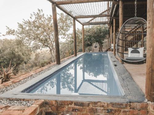 a swimming pool in a house with a swing at Thaba eNtle Private Boutique Game Farm in Thabazimbi