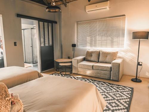 a bedroom with a bed and a couch and a chair at Thaba eNtle Private Boutique Game Farm in Thabazimbi