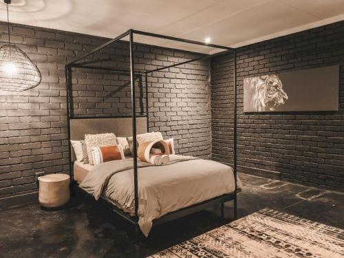 a bedroom with a metal canopy bed in a brick wall at Thaba eNtle Private Boutique Game Farm in Thabazimbi
