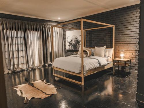 a bedroom with a canopy bed and a brick wall at Thaba eNtle Private Boutique Game Farm in Thabazimbi