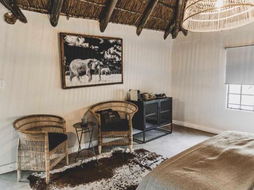 a bedroom with two chairs and a picture of elephants on the wall at Thaba eNtle Private Boutique Game Farm in Thabazimbi