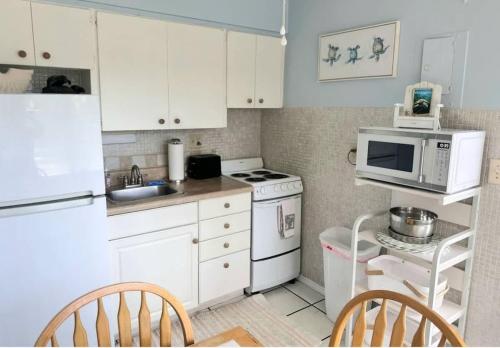een kleine keuken met witte kasten en een magnetron bij BEACH Zen Oasis-walk 2 beaches in Deerfield Beach