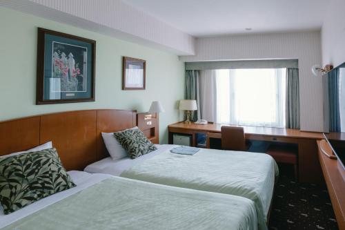 a hotel room with two beds and a desk at Hotel Boston Plaza Kusatsu in Kusatsu