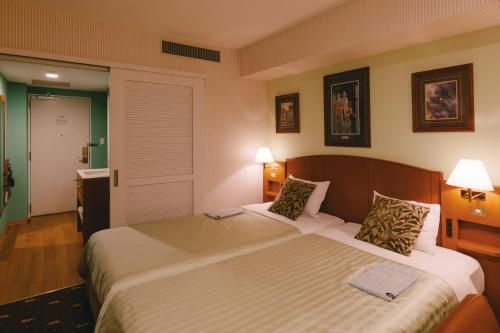 a bedroom with a large bed with two pillows at Hotel Boston Plaza Kusatsu in Kusatsu