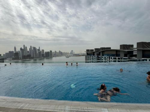 two people in a swimming pool with a city in the background at Dubai Palm Jumeirah - Free Infiniti Pool and Private Beach in Dubai