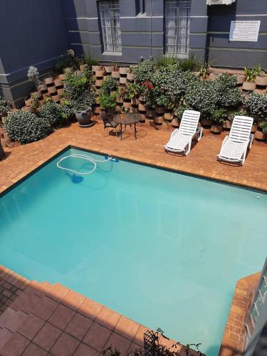 a swimming pool with two lawn chairs and a table and two lounge chairs at Airport Inn and Suites in Johannesburg