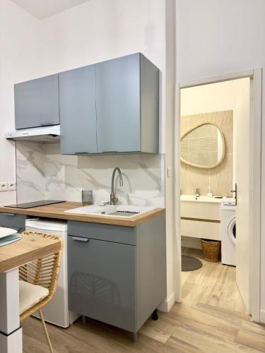 une cuisine avec des armoires bleues et un évier dans l'établissement Le cocon du Roi Jérôme - Hypercentre, à Ajaccio