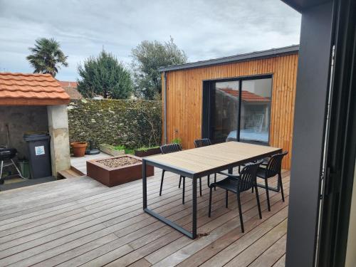 une terrasse en bois avec une table et des chaises dessus dans l'établissement L'Inattendu, à Pornic