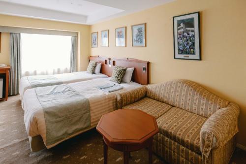 a hotel room with a bed and a couch at Hotel Boston Plaza Kusatsu in Kusatsu