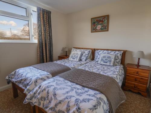 Un dormitorio con dos camas y una ventana. en Broadstones, en Bridport