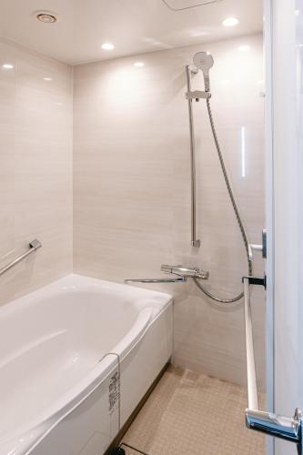 a bathroom with a bath tub and a shower at Hotel Boston Plaza Kusatsu in Kusatsu