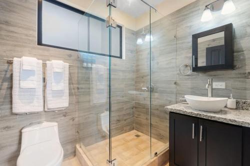 a bathroom with a glass shower with a toilet and a sink at Suite 3 Jaguar - Beach & Pool 2 BR Condo in Brasilito